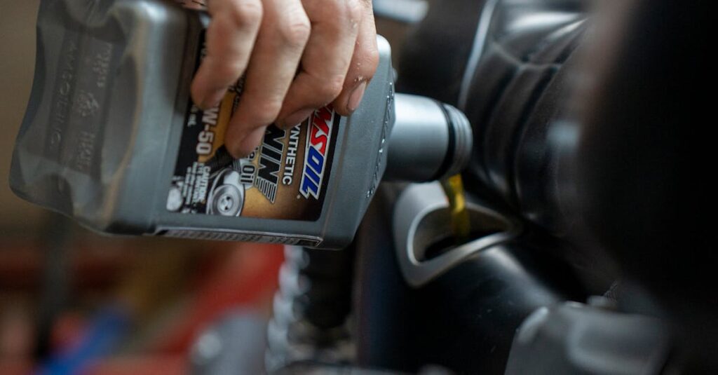 Close-up of a mechanic pouring engine oil into a motorcycle inside a garage.